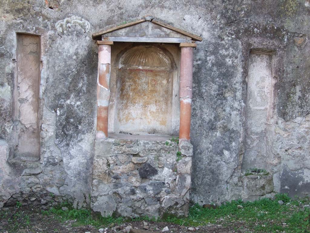 VII.3.6 Pompeii. December 2006. Aedicula lararium against south wall of garden area.
According to Boyce –
above a rectangular podium (1.05 by 0.50, height 0.95) stand two columns (h. 1.0) coated with red stucco.
These supported the roof with pediment. 
The semi-circular niche in the rear wall had its vaulted ceiling adorned with a stucco shell.
The walls of the niche were painted orange and on each side of the niche was a stucco pilaster.
A large marble statuette of Venus Anadyomene (H.0.72) was found in the aedicula.
On either side of the aedicula are two long vertical slits, Fiorelli suggested they may have held candelabra.
See Boyce G. K., 1937. Corpus of the Lararia of Pompeii. Rome: MAAR 14.  (p. 63, no: 259 and pl. 36, 1).
See Giacobello, F., 2008. Larari Pompeiani: Iconografia e culto dei Lari in ambito domestico. Milano: LED Edizioni, (p.280 no.V64)