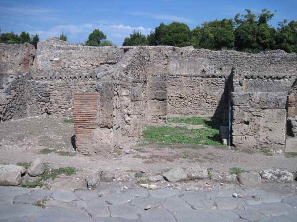 I.1.5 Pompeii. September 2010. Entrance on Via Stabiana, looking east.
Photo courtesy of Drew Baker.
According to Warscher, quoting Mau in Bull. Inst. 1875, p.29, 
I.1.4/5 - “Mentre le località servivano per i carri e per il bestiame da tiro e come camere da letto, lungo la strada, a sinistra dello ingresso, stanno altre località (nos.4 and 5) che evidentemente servivano da caupona per i carrettieri e per altri avventori.  Vi sono due locali con larga apertura sulla strada, a guisa di botteghe, congiunte mediante una porta, e in ciascuno di cui dà un’altra stanza con apertura larga anch’essa, queste ultime non congiunte fra di loro, mentre quella meridionale ha una porta su quel locale per cui si passa nel cortile. In mezzo al locale anteriore no.4 si trova una tavola di materiale piuttosto piccola, sulla quale si metteva senza dubbio una tavola più grande di legno per mangiare.  Avanti alla porta del locale no.5 e lungo il muro laterale della casa adiacente, che sporge un poco nella strada, vi è una panca di materiale, quale trovammo avanti alla caupona (also see I.1.6/9)
See Warscher T., 1936. Codex Topographicus Pompeianus: Regio I.1, I.5. (no.13), Rome: DAIR, whose copyright it remains.
See Warscher T., 1936. Codex Topographicus Pompeianus: Regio I.1, I.5. (no.13), Rome: DAIR, whose copyright it remains.
(translation: “While the locality served for wagons and animals and as sleeping accommodation, along the road, to the left of the entrance, were other places (nos. 4 and 5) that evidently served as caupona for the carters and other patrons.  There were two rooms with a wide opening onto the road in the guise of shops, joined through a door, and in each of which had another different room also with a wide opening, these last did not join each other, while the southern one had a door which passed into the courtyard. In the middle of the front room of no. 4 was a table of material, rather small, on which one would undoubtedly have placed a larger wooden table for eating. Before the door of the premises no. 5 and along the side wall of the adjacent house, which protruded a little onto the street, there was a bench of material, which was found before the caupona”.)