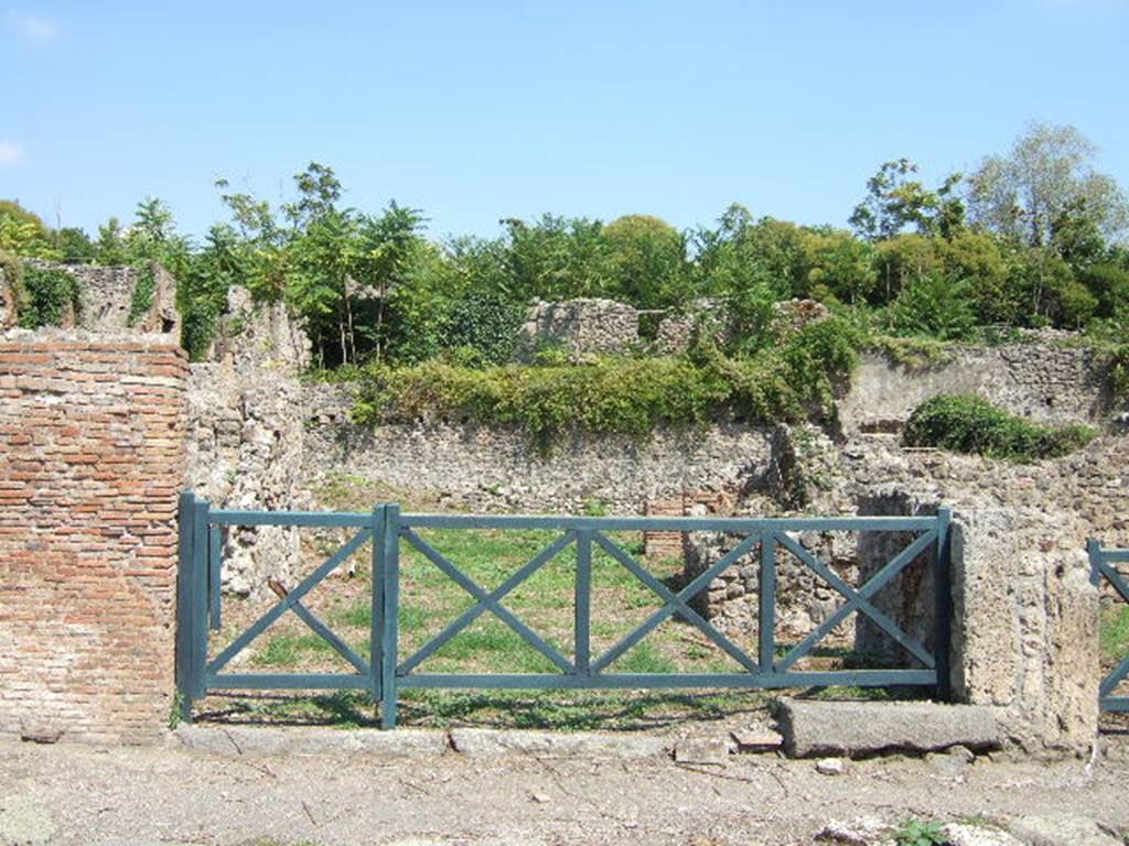 I.1.8 Pompeii, on left, and I.1.7 Pompeii, stairs to upper floor, on right. September 2005.
According to Warscher, quoting Mau in Bull.Inst 1875, p.30, I.1.6-9: “Segue un altro albergo, molto simile a questo descritto.  Qui pure è interrotto il marciapiede per lasciar entrare i legni. L’entrata era chiuse mediante una porta a quattro partiti, congiunti a due adue, come si conosce dai quattro buchi per i chiavistelli.  Qui pure si entra prima in un compreso che ha le dimensioni d’una bottega grande con una dietrobottega e posteriormente si apre sopra una grande corte, lungo il cui muro di fondo qui pure si stende la stalla, larga 13,30, profonda 2,47 con una finestra sul vico settentrionale e due porte, una all’estremità meridionale, l’altra poco distante da quella settentrionale. 
Presso a quest’ultima una parte della corte è selciata.  Lungo il muro N vi sono due camere con finestre sul medesimo vico, e prossimo alla stalla il cesso.  Si vede anche il cesso del piano superiore e i tubi di mattone d’un terzo, che stava ancora più in alto.  
Nell’angolo NO vi sono I primi gradini d’una scala, la cui parte superiore sarà stata di legno, in quello SO l’apertura della cisterna, e accanto nella stessa massa di materiale una vasca lunga stretta e bassa, come quella sudescritta nella casa adiacente. Qui la vediamo frapposto fra la cisterna ed il muro di O, il che esclude categoricamente l’aver essa servito d’abbeveratoio. Dalla parte più bassa di essa, aperta come nella casa sudescritta, l’acqua colava in un’altra vasca larga 1,02 x 1,54, di cui un lato viene formato dalla suddetta massa di fabbrica, uno dal muro occidentale, i due rimanenti da appositi muricciuoli.  Essa ha al fondo uno scolo verso N, che dà in un vaso ossia tubo di mattone, incastrato nel suolo. Nella parete vi era la pittura dei Lari, di cui sono rimasti soltanto i serpi. A destra dell’ingresso per i legni sta un locale come una bottega. 
L’essere esso congiunto mediante una porta con quel primo compreso, ove entravano i legni, ci lascia supporre, aver esso servito di caupona per i vetturini”.
See Warscher T., 1935. Codex Topographicus Pompeianus: Regio I.1/I.5. Rome: DAIR. (no.14)
(for a translation see, I.1.6).