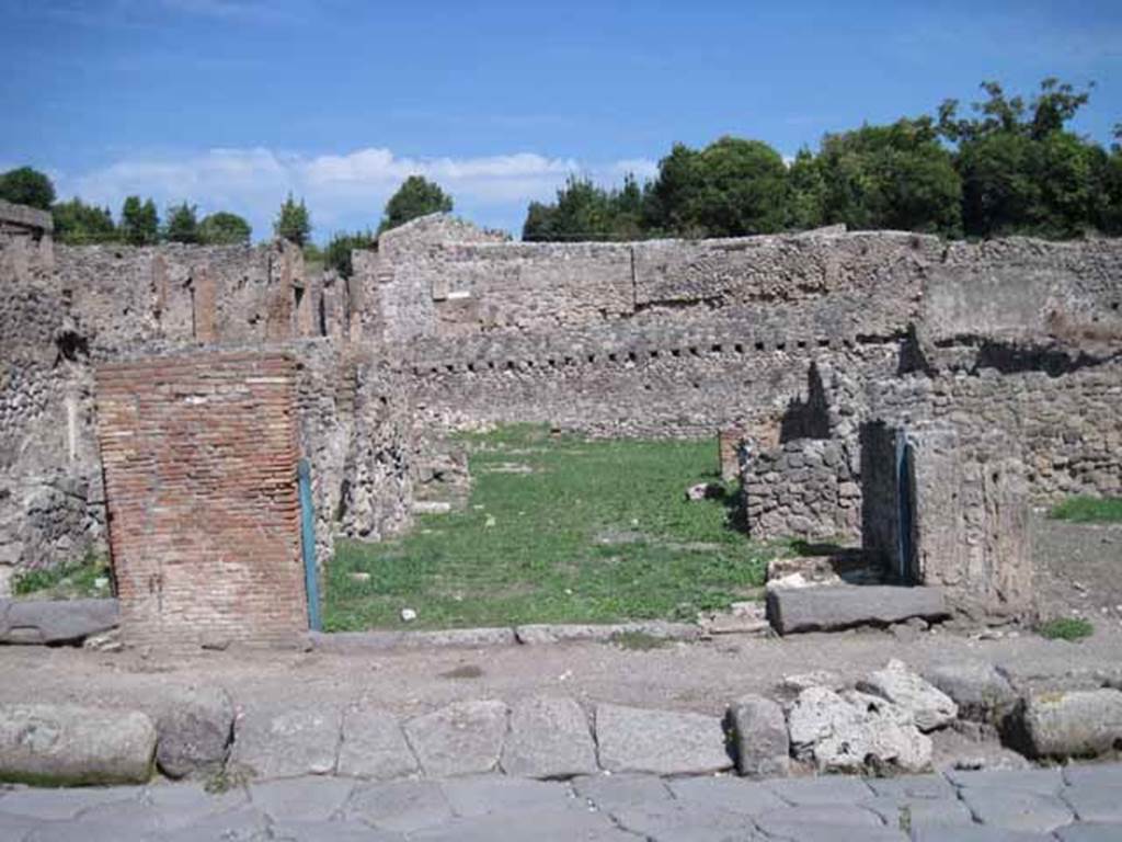 I.1.8 Pompeii. September 2010. Entrance doorway, looking east from Via Stabiana.
The entrance for I.1.7 is on the right side of the entrance). Photo courtesy of Drew Baker.
According to Warscher, quoting Mau in Bull.Inst 1875, p.30, I.1.6-9: “Segue un altro albergo, molto simile a questo descritto.  Qui pure è interrotto il marciapiede per lasciar entrare i legni. L’entrata era chiuse mediante una porta a quattro partiti, congiunti a due adue, come si conosce dai quattro buchi per i chiavistelli.  Qui pure si entra prima in un compreso che ha le dimensioni d’una bottega grande con una dietrobottega e posteriormente si apre sopra una grande corte, lungo il cui muro di fondo qui pure si stende la stalla, larga 13,30, profonda 2,47 con una finestra sul vico settentrionale e due porte, una all’estremità meridionale, l’altra poco distante da quella settentrionale. 
Presso a quest’ultima una parte della corte è selciata.  Lungo il muro N vi sono due camere con finestre sul medesimo vico, e prossimo alla stalla il cesso. Si vede anche il cesso del piano superiore e i tubi di mattone d’un terzo, che stava ancora più in alto.  
Nell’angolo NO vi sono I primi gradini d’una scala, la cui parte superiore sarà stata di legno, in quello SO l’apertura della cisterna, e accanto nella stessa massa di materiale una vasca lunga stretta e bassa, come quella sudescritta nella casa adiacente. Qui la vediamo frapposto fra la cisterna ed il muro di O, il che esclude categoricamente l’aver essa servito d’abbeveratoio. Dalla parte più bassa di essa, aperta come nella casa sudescritta, l’acqua colava in un’altra vasca larga 1,02 x 1,54, di cui un lato viene formato dalla suddetta massa di fabbrica, uno dal muro occidentale, i due rimanenti da appositi muricciuoli.  Essa ha al fondo uno scolo verso N, che dà in un vaso ossia tubo di mattone, incastrato nel suolo. Nella parete vi era la pittura dei Lari, di cui sono rimasti soltanto i serpi. A destra dell’ingresso per i legni sta un locale come una bottega. 
L’essere esso congiunto mediante una porta con quel primo compreso, ove entravano i legni, ci lascia supporre, aver esso servito di caupona per i vetturini”.
See Warscher T., 1935. Codex Topographicus Pompeianus: Regio I.1/I.5. Rome: DAIR. (no.14)
(for a translation see, I.1.6).