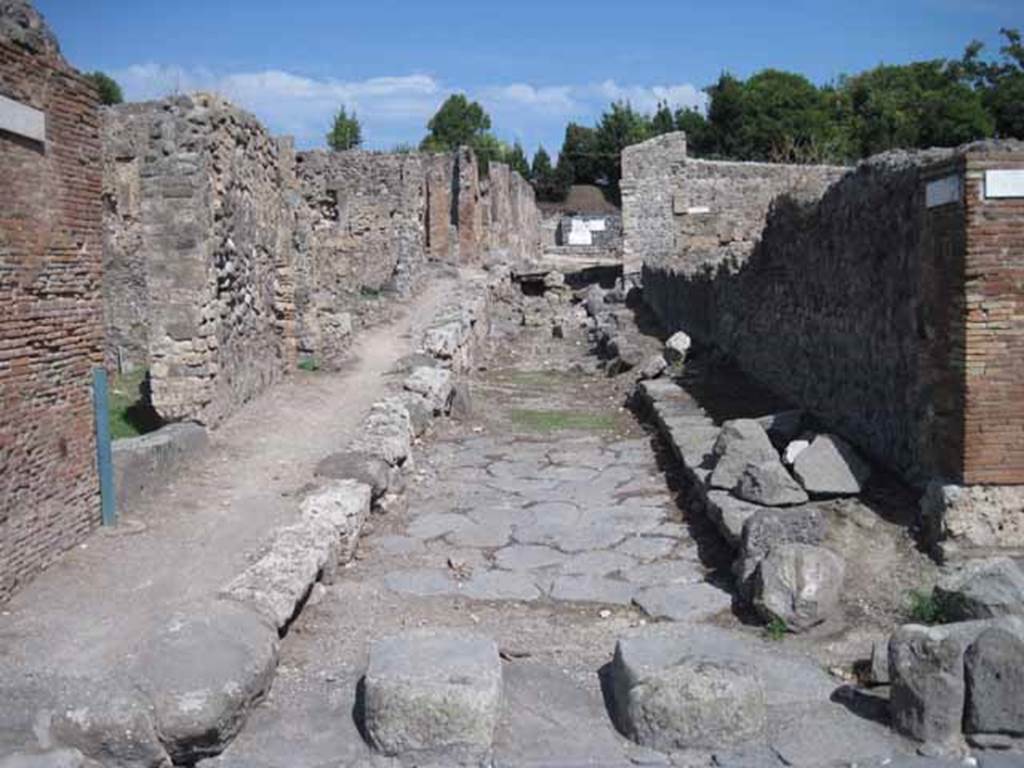 I.2 Pompeii, on left. September 2010. Looking east along Vicolo del Conciapelle, with the north (side) wall of  I.1.9, on right. Photo courtesy of Drew Baker.