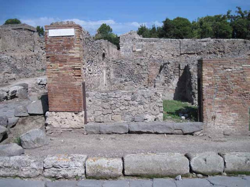 I.1.9 Pompeii. September 2010. Entrance doorway, looking east from Via Stabiana.
Photo courtesy of Drew Baker.
According to Warscher, quoting Mau in Bull.Inst 1875, p.30, I.1.6-9: “Segue un altro albergo, molto simile a questo descritto.  Qui pure è interrotto il marciapiede per lasciar entrare i legni. L’entrata era chiuse mediante una porta a quattro partiti, congiunti a due adue, come si conosce dai quattro buchi per i chiavistelli. Qui pure si entra prima in un compreso che ha le dimensioni d’una bottega grande con una dietrobottega e posteriormente si apre sopra una grande corte, lungo il cui muro di fondo qui pure si stende la stalla, larga 13,30, profonda 2,47 con una finestra sul vico settentrionale e due porte, una all’estremità meridionale, l’altra poco distante da quella settentrionale. 
Presso a quest’ultima una parte della corte è selciata.  Lungo il muro N vi sono due camere con finestre sul medesimo vico, e prossimo alla stalla il cesso. Si vede anche il cesso del piano superiore e i tubi di mattone d’un terzo, che stava ancora più in alto.  
Nell’angolo NO vi sono I primi gradini d’una scala, la cui parte superiore sarà stata di legno, in quello SO l’apertura della cisterna, e accanto nella stessa massa di materiale una vasca lunga stretta e bassa, come quella sudescritta nella casa adiacente. Qui la vediamo frapposto fra la cisterna ed il muro di O, il che esclude categoricamente l’aver essa servito d’abbeveratoio. Dalla parte più bassa di essa, aperta come nella casa sudescritta, l’acqua colava in un’altra vasca larga 1,02 x 1,54, di cui un lato viene formato dalla suddetta massa di fabbrica, uno dal muro occidentale, i due rimanenti da appositi muricciuoli.  Essa ha al fondo uno scolo verso N, che dà in un vaso ossia tubo di mattone, incastrato nel suolo.Nella parete vi era la pittura dei Lari, di cui sono rimasti soltanto i serpi.A destra dell’ingresso per i legni sta un locale come una bottega. 
L’essere esso congiunto mediante una porta con quel primo compreso, ove entravano i legni, ci lascia supporre, aver esso servito di caupona per i vetturini”.
See Warscher T., 1935. Codex Topographicus Pompeianus: Regio I.1/I.5. Rome: DAIR. (no.14)
(for a translation see, I.1.6).