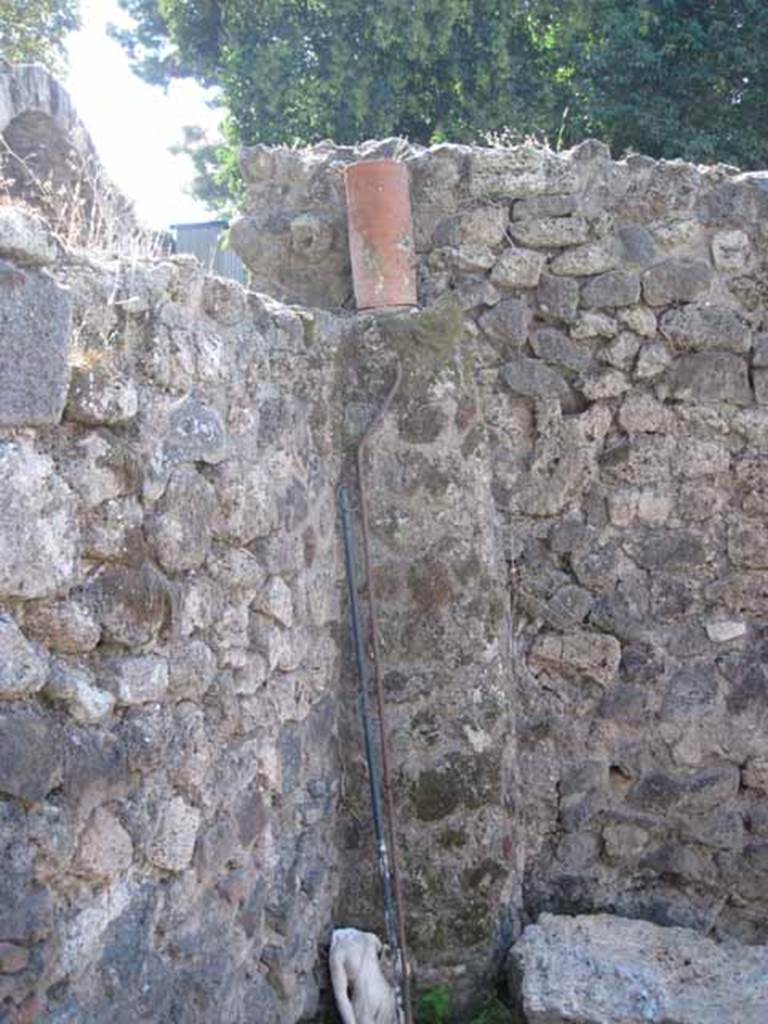 I.1.10 Pompeii. September 2010.  Looking west towards south-west corner of room with doorway leading to I.1.1. Detail of feature down-pipe.  Photo courtesy of Drew Baker.