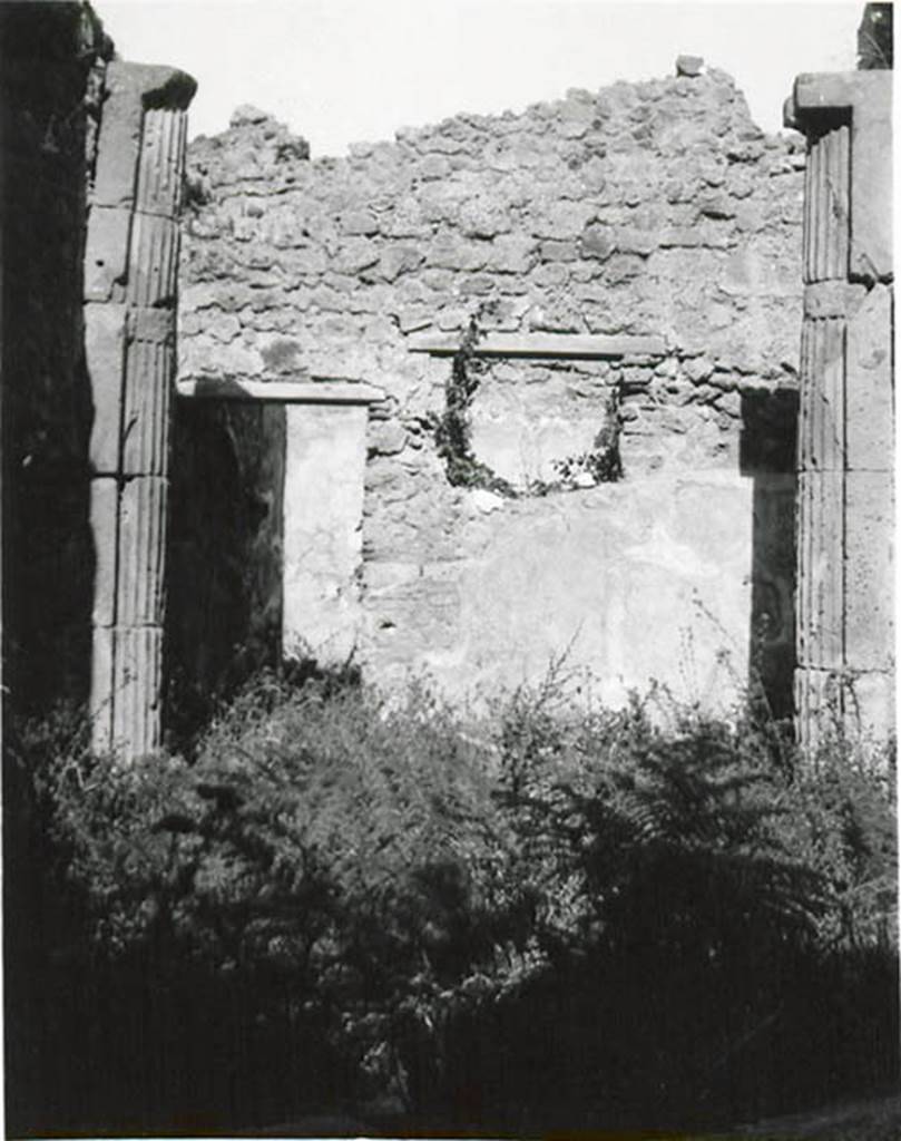 I.2.3 Pompeii. 1935 photo taken by Tatiana Warscher. Looking north.
Warscher described this photo as – I.2.3 “Il triclinio (h): una specie di piccolo vestibulo a sinistra (nord) è ornato con due mezzocolonne di tufo scannelate.  Non è rimasto niente nè della pittura del Genio familiare che libava, nè del dipinto del gallo sull’ara. In connessione con la colonna intercalata nel muro nord della prima camera a sinistra dell’atrio (photo no.8) facciamo attenzione che nel muro occidentale del triclinio sono intercalati due tamburi d’una colonna.  Forse il proprietario ricostruendo la casa dopo il terremoto dell’anno 63 ha acquistato una colonna, due tamburi e anche due mezzocolonne scannellate. 
Quoting Sogliano, no.58 on page 18, she described: Cella penaria: “Serpente che si accosta all’ara imbandita di offerte; al di sotto piante palustri e al di sopra tre piccoli festoni di foglie, sormontati ciascuno da un uccelletto”.
See Sogliano, A., 1879. Le pitture murali campane scoverte negli anni 1867-79. Napoli: Giannini. (p.18, no.58)
See Warscher T., 1935. Codex Topographicus Pompeianus: Regio I.2. (no.11), Rome: DAIR, whose copyright it remains.   
(translation: I. 2.3 "triclinium (h): a small vestibule on the left (north side) was adorned with two fluted tufa half-columns.  There remained nothing of the painting of the family Genius making the offering, nor of the painting of the cock painted on the altar.  In connection with the column inserted in the northern wall of the room to the left of the entrance hall (photo no. 8) we draw attention that in the west wall of the triclinium were interspersed two column drums.  Maybe the owner by rebuilding the house after the earthquake of the year 63 had bought a column, two drums and also two fluted half-columns”. 
Quoting Sogliano, no. 58 on page 18, she described: 
Storeroom : "Serpent approaching the altar table laid with offerings; marsh plants below and three small garlands festoons of foliage above, each surmounted by a bird”.)