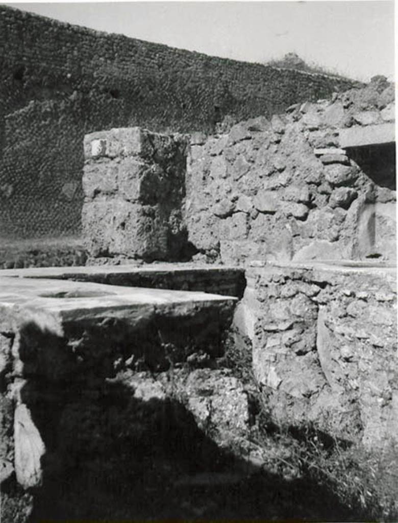 I.2.8 Pompeii. 1935 photo taken by Tatiana Warscher. Looking north-west across bar-counters towards north wall with niche. Warscher described –
I.2.8 “una taberna col podio continente due urne altre il focolaio, ed altro podio da un lato, in qui stanno infisse tre urne di maggiore dimensione: 
un muro divideva questo primo compreso da un secundo più interno, ove sembra fossero collocati due letti, e serviva anche di sostegno ad una scala, che portava alle stanze sovrapposte”.
See Warscher T., 1935. Codex Topographicus Pompeianus: Regio I.2. (after no.20), Rome: DAIR, whose copyright it remains.