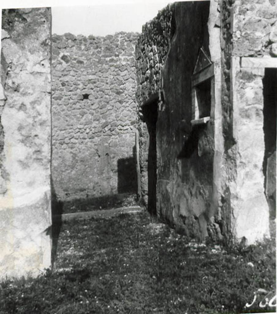 1.2.17 Pompeii. 1935 photo taken by Tatiana Warscher. Looking north along entrance corridor towards doorway.
See Warscher T., 1935. Codex Topographicus Pompeianus: Regio I.2. (no.28), Rome: DAIR, whose copyright it remains.
According to Warscher, quoting Bull. Inst, 1874, p.264 – I.2.17 “La fauces che hanno la soglia di lava, s’abbassano un poco verso l’interno.  Nel muro sinistra vi è una piccola nicchia con suole e cornice di marmo a guisa d’un tempietto. Nel suole di essa sono tre buchi, uno più profondo degli altri destinati probabilmente per mettervi piccoli idoli, come la lastra sporgente del suolo serviva per oblazioni. Presso gli angoli che formano le fauces coll’atrio manca lo stucco del muro, e nel suolo su ciascun lato si vede una pietra di lava: evidentemente vi stavano li postes di legno”.
(translation: I.2.17 “The fauces that had a threshold of lava, led slightly downwards towards the atrium. In the left wall there was a small niche with floor and cornice of marble, in the guise of a shrine. In the floor were three holes, one deeper than the others, which was used probably for a small idol, and the protruding slab of the floor was used for donations. Near the corner that joined the fauces with the atrium, the wall stucco was missing and in the floor on that side one could see a slab of lava: evidently there were wooden posts”.)