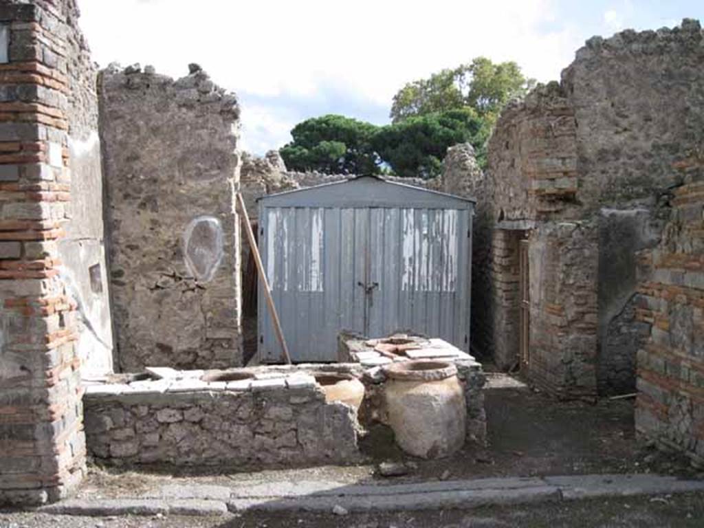 I.2.18 Pompeii. September 2010. Looking south towards entrance doorway and remains of north side of podium with dolia.Photo courtesy of Drew Baker.