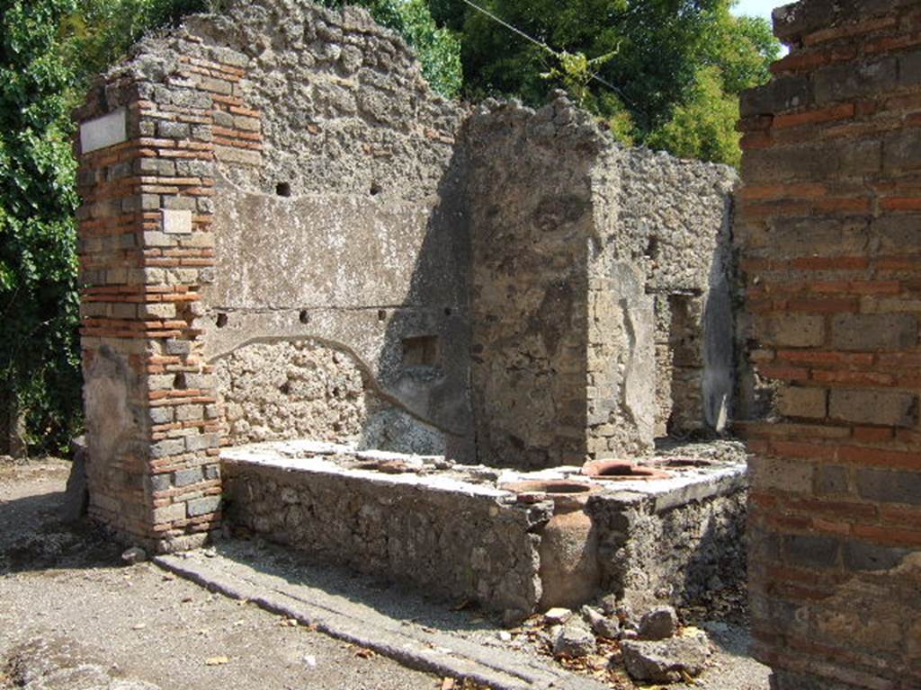 I.2.18 Pompeii. September 2005. Counter with urns. Fiorelli described this as having a podium of marble, containing 6 big terracotta urns of varying sizes, one of which was covered and fastened by a bolt of iron.
See Pappalardo, U., 2001. La Descrizione di Pompei per Giuseppe Fiorelli (1875). Napoli: Massa Editore. (p.36)
According to Warscher – I.2.18/19 “Il termopolio all’angolo del vico di Tesmo e della via secunda. Ha il podio rivestito superiormente di marmo, contenente sei urne di terracotta di diversa grandezza, una delle quali chiudevasi con coperchio di tavole fermato da spranga di ferro. Erano poggiate alle pareti due scansie di legno, e vi stava pure incavata in piccola nicchia dei Penati; mentre dall’opposto lato esisteva una cella rustica, con ammezzato di sopra, al quale accedevasi mercè di scala portatile”.
See Warscher T., 1935. Codex Topographicus Pompeianus: Regio I.2. Rome: DAIR, whose copyright it remains.
(translation: I. 2.18/19 “Thermopolium on the corner of Vico di Tesmo and Via Secunda. It had the podium covered by a marble counter-top, containing six terracotta urns of different sizes, one of which was closed with a lid which was closed with an iron bolt. Two wooden shelves were leaning against the wall, and there was a small niche of the Penates embedded in the wall, while on the opposite side there was a rustic cell with a mezzanine level above, to which one gained access by a portable stairs”.)