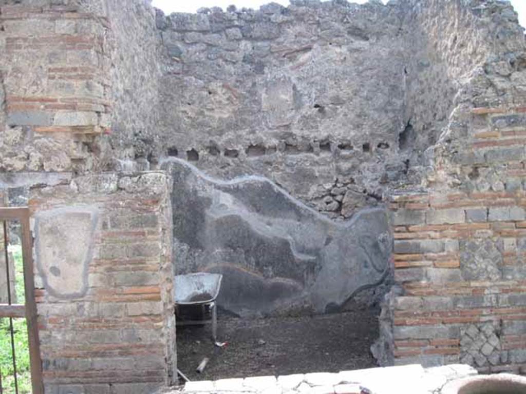 I.2.18 Pompeii. September 2010. Looking west from bar towards small room, possibly a kitchen and doorway to peristyle of I.2.17. Photo courtesy of Drew Baker.
According to Boyce, in the south-west corner of the kitchen, built in a peculiar manner, was an arched niche. (height 0.30, w.0.30, d.0.25, height above the floor 1.30). See Boyce G. K., 1937. Corpus of the Lararia of Pompeii. Rome: MAAR 14. (p.22, no.12)