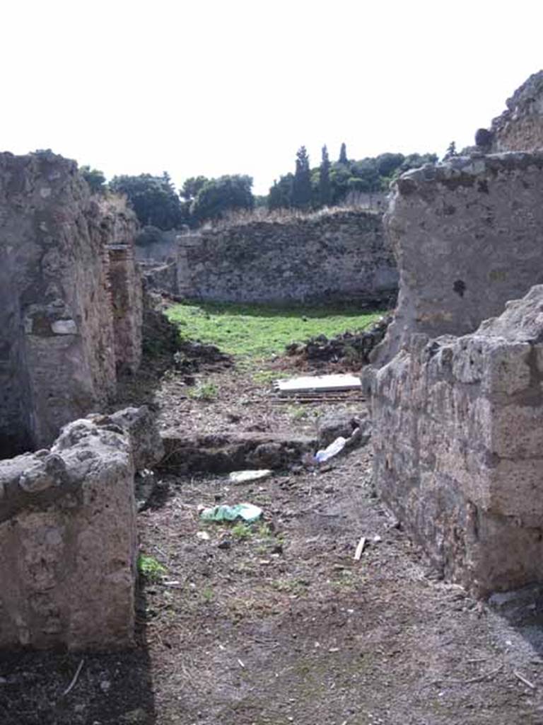 I.2.20 Pompeii. September 2010. Looking west towards entrance doorway. Photo courtesy of Drew Baker.  According to Warscher, quoting Fiorelli, she described –
“Entrambi I due aditi appartenevano ad una caupona, cui era congiunto un thermopolium. La caupona no.20 teneva a destra dell’androne una cella, e poi un cortile con banco di fabbrica per sedere: a sinistra la cucina, la latrina, il pozzo, ed un piccola apotheca, dove rimangono ancora sulle pareti i chiodi di sostegno alle scansie.  Il cortile, o atrio che voglia dirsi, veniva illuminato da un finestra sporgente in un attiguo viridario, il cui ambulacro sottoposto ad un tettoia, conduceva al triclinio, ad un scaletta montante ai cenacoli, e ad altre due celle destinate forse agli avventori.  Addossati ad un angolo del viridario stanno due letti triclinarii di fabbrica, con la loro mensa, e sulla parete accosto è tracciata col carbone, di mezzo a varie epigrafi, una testa muliebre di grandezza maggiore del vero, forse di quella stessa Serena, che forni argomento a varie di queste scritture.  Sulla parete a destra vedesi il sacrario dei Penati, consistente di una nicchia, presso cui è l’immagine di un grosso serpente cristato, che passa fra varie piante e si avvicina ad una mensa, sulla quale stanno imbandite varie frutta ed una pigna: superiormente sono effigiati Bacco e la Fortuna, ai lati dei globo terrestro, cui è adossata la luna crescente sormontata dall’astro, e tutto sotto due festoni di foglia”.
See Fiorelli, Descrizione, p.45/46.
See Pappalardo, U., 2001. La Descrizione di Pompei per Giuseppe Fiorelli (1875). Napoli: Massa Editore. (p.36)
See Warscher T., 1935. Codex Topographicus Pompeianus: Regio I.2. Rome: DAIR, whose copyright it remains
(translation: “Both the two accesses belonged to one caupona, which was joined to the thermopolium. On the right of the entrance doorway to the caupona at no.20 was a room, and then a courtyard with a masonry bench for sitting: on the left, the kitchen, latrine, the well, and a small storeroom, where the nails to support shelving on the walls still remained.  The courtyard, or atrium, was illuminated by a projecting window in an adjoining garden, whose walkway under a roof, led to the triclinium, to a stairway going up to the upper dining rooms, and to another two rooms destined perhaps for the patrons.  Close to a corner of the garden were two masonry triclinium couches, with their table, and on the wall nearby was drawn with charcoal, among various other epigraphs, a head of a woman, larger than life, maybe that of the same Serena that was mentioned in several of these writings.  On the wall to the right, we see the shrine of the Penates, consisting of a niche, near to which was the image of a crested serpent, that passed between various plants while approaching a table, on which were laid out various fruits and a pine-cone: above were the effigies of Bacchus and Fortuna, to the side of the terrestrial globe which was attached to the crescent moon with a star above it, above all were two garlands of foliage”.)