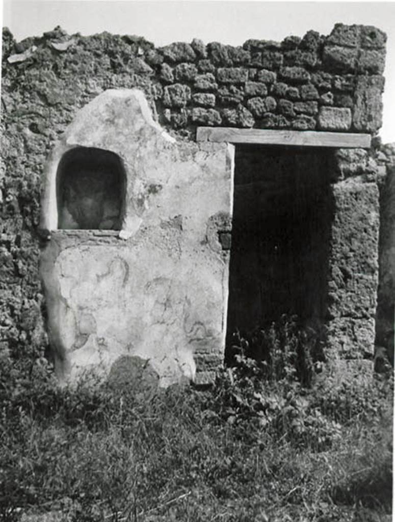 I.2.24 Pompeii. 1935 photo taken by Tatiana Warscher.
Looking towards south wall of atrium, with niche and doorway to understairs area.
See Warscher T., 1935. Codex Topographicus Pompeianus: Regio I.2. (no.45), Rome: DAIR, whose copyright it remains.
According to Boyce, on the south side of the atrium was the lararium.
Above an arched niche was painted a cylindrical altar (tripod according to Fiorelli) with a Genius pouring a libation.
Standing beside him was the tibicen and to the left was a Lar. The Lar on the right was not preserved.
Below the niche were the two serpents.
On the wall on each side of the niche was painted a large dog?
The one on the left was poorly preserved but was seen to be lying down, while the one on the right was opening his mouth wide.
From the hindquarters of this second dog there projected horizontally the upper half of the body of a man.
See Boyce G. K., 1937. Corpus of the Lararia of Pompeii. Rome: MAAR 14. (p.23, no.16 and Pl.2,2) 
See Sogliano, A., 1879. Le pitture murali campane scoverte negli anni 1867-79. Napoli: Giannini. (p.17, no.46).