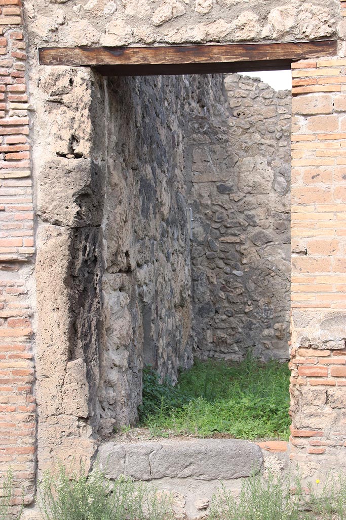 I.2.26 Pompeii. October 2024. 
Looking north through doorway into site of stairs to upper floor dwelling and workshop.
Photo courtesy of Klaus Heese.
