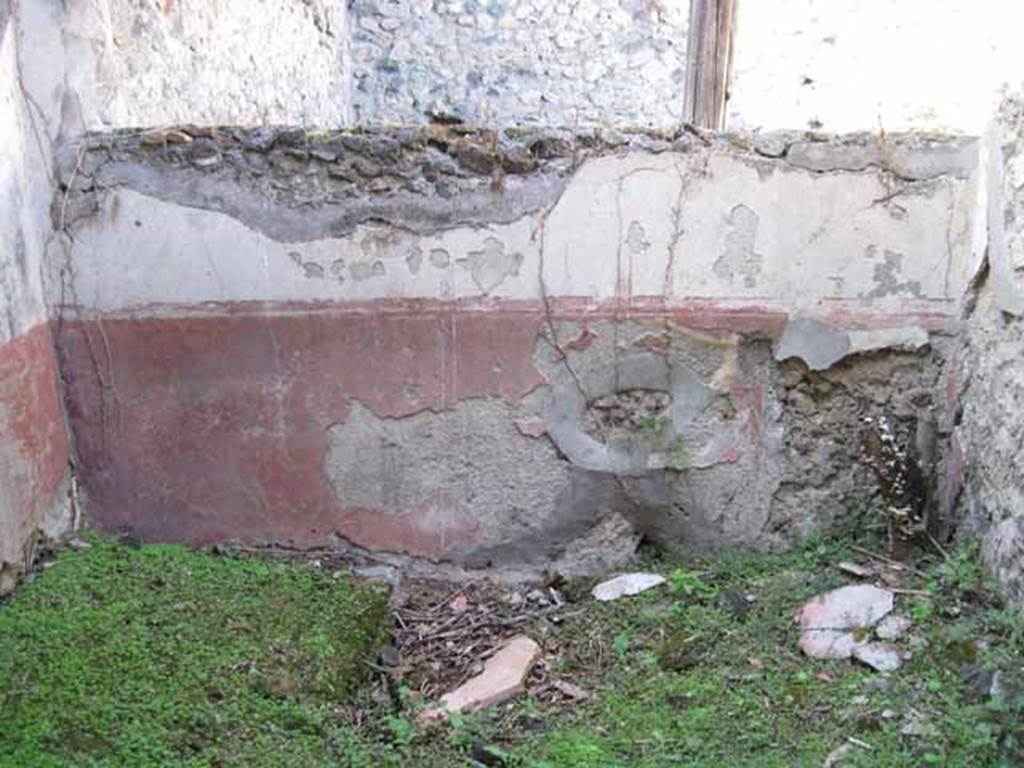 I.2.28 Pompeii. September 2010. North wall of room on south side of triclinium, with window onto garden area. Photo courtesy of Drew Baker.
According to Fiorelli, this room had access to a short underground passage for keeping provisions. See Pappalardo, U., 2001. La Descrizione di Pompei per Giuseppe Fiorelli (1875). Napoli: Massa Editore. (p.37)
According to Warscher, quoting Mau in Bull. Inst, 1874, p.250/51, she wrote –
“Il peristilio, situate piu alto dell atrio a causa del terreno inuguale, ha corridoi di 3 e 3 colonne sui lati S ed E, mentre verso N ed O confina con le case adiacenti (I.2.17; I.2.22; I.2.24).  
Le colonne sono di mattoni e di stucco rozzo, color di carne fino all’altezza del muriciuolo che le congiunge, bianco di sopra.
La parte occidentale del portico meridionale, posteriormente soltanto, come ci fa testimonianza lo stucco delle colonne, coperto dal muro, ne fu separato e trasformata in una camera, che mediante una porta corrisponde colla camera a sinsitra del tablino, mentre verso N con una finestra larga, distante dal suolo m.1,52, si apre sul peristilio.
Sotto il pavimento di questa camera v’è un cavo, largo m. 0,98 + 0,67, profondo m. 1,32, rivestito di stucco e di sopra a metà coperto, mentre l’apertura che rimane evidentemente doveva chiudersi con un coperchio.
Sifatto cavo, il primo di questa sorta che si sia trovato a Pompei, serviva senza dubbio per conservare tutto ciò, cher si voleva difendere dal caldo, facendo così le veci d’una piccola cantina.
Sul lato meridionale del peristilio vi è ancora un armadio stretto, aperto verso O, ed il cui fondo viene formato dal muro occidentale della camera a destra dell’atrio, la quale sporge un poco nel peristilio”.