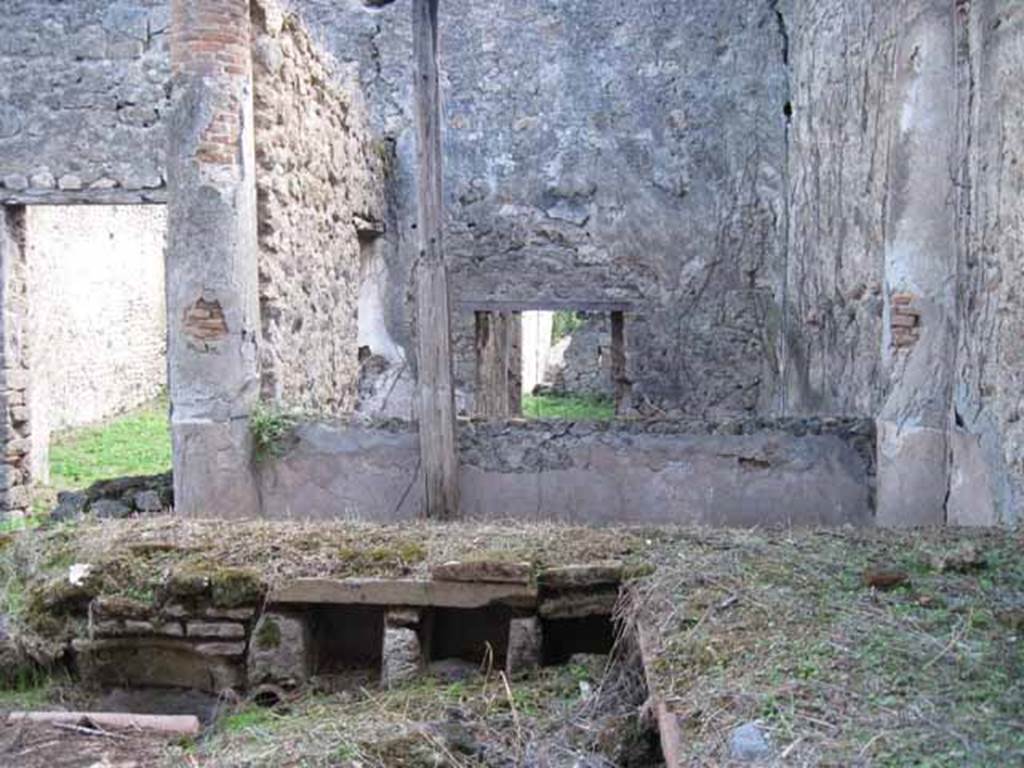 I.2.28 Pompeii. September 2010. Looking south across triclinium towards rear room with window, and doorway to tablinum (on left). Photo courtesy of Drew Baker.
According to Warscher, “Il triclinio occupa la parte opccidentale del pseudo-peristilio. 
Si vedono quattro buchi rettangolari che illuminavano il sotterraneo; l’ingresso a questo ultimo è dalla stanza adiacente (a sinistra nella fotografia no.54 (stanza L)”.
According to Warscher, quoting Mau in Bull. Inst, 1874, p.250/51, she wrote –
“Il peristilio, situate più alto dell atrio a causa del terreno inuguale, ha corridoi di 3 e 3 colonne sui lati S ed E, mentre verso N ed O confina con le case adiacenti (I.2.17; I.2.22; I.2.24).  Le colonne sono di mattoni e di stucco rozzo, color di carne fino all’altezza del muriciuolo che le congiunge, bianco di sopra. La parte occidentale del portico meridionale, posteriormente soltanto, come ci fa testimonianza lo stucco delle colonne, coperto dal muro, ne fu separato e trasformata in una camera, che mediante una porta corrisponde colla camera a sinistra del tablino, mentre verso N con una finestra larga, distante dal suolo m.1,52, si apre sul peristilio. Sotto il pavimento di questa camera v’è un cavo, largo m. 0,98 + 0,67, profondo m. 1,32, rivestito di stucco e di sopra a metà coperto, mentre l’apertura che rimane evidentemente doveva chiudersi con un coperchio. Sifatto cavo, il primo di questa sorta che si sia trovato a Pompei, serviva senza dubbio per conservare tutto ciò, che si voleva difendere dal caldo, facendo così le veci d’una piccola cantina. Sul lato meridionale del peristilio vi è ancora un armadio stretto, aperto verso O, ed il cui fondo viene formato dal muro occidentale della camera a destra dell’atrio, la quale sporge un poco nel peristilio”.
See Warscher T., 1935. Codex Topographicus Pompeianus: Regio I.2. Rome: DAIR, whose copyright it remains.
(translation: "The peristyle, situated higher than the atrium due to the uneven ground, had a walkway of 3 and 3 columns on the south and east sides, while towards the north and west it was bordered with the adjacent homes (I. 2.17; I. 2.22; I. 2.24). The columns were of brick and rough stucco, red-coloured up to a height of a wall that joined them, white above.  As could be seen by the stucco of the columns covered by the wall, the western part of the south portico at the rear only, was separated and transformed into a room, that by means of a door joined with the room to the left of the tablinum, while towards the north, 1,52 m distance from ground,  a large window opened onto the peristyle. Under the floor of this room there was a pit, 0,98m + 0.67 width, 1,32 m deep, faced with stucco and half covered above, while the opening that remained obviously would need to close with a lid. Such a pit, the first of its kind to be found at Pompeii, was undoubtedly to preserve everything, that you wanted to protect from the heat, thus making this the place of a small cellar. On the south side of the peristyle there was still a narrow cupboard, open towards the west, and whose base was formed by the west wall of the room to the right of the atrium, which protruded a little onto the peristyle ".)