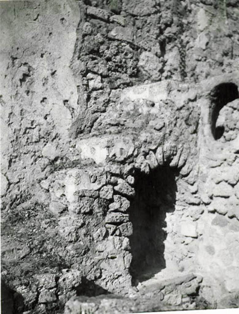 I.2.28 Pompeii. 1935 photo taken by Tatiana Warscher.  North-east corner of garden area, with steps to upper floor and recess below.
See Warscher T., 1935. Codex Topographicus Pompeianus: Regio I.2. (no.57), Rome: DAIR, whose copyright it remains.
According to Warscher, “Il lato orientale del peristilio. La scala con sottoscala che conduceva al primo piano e la finestra ovale che illuminava la cucina “k”.
(translation: “The east side of the peristyle. The stairs with understairs, that lead to the first floor, and the oval window that lit the kitchen “k”.)