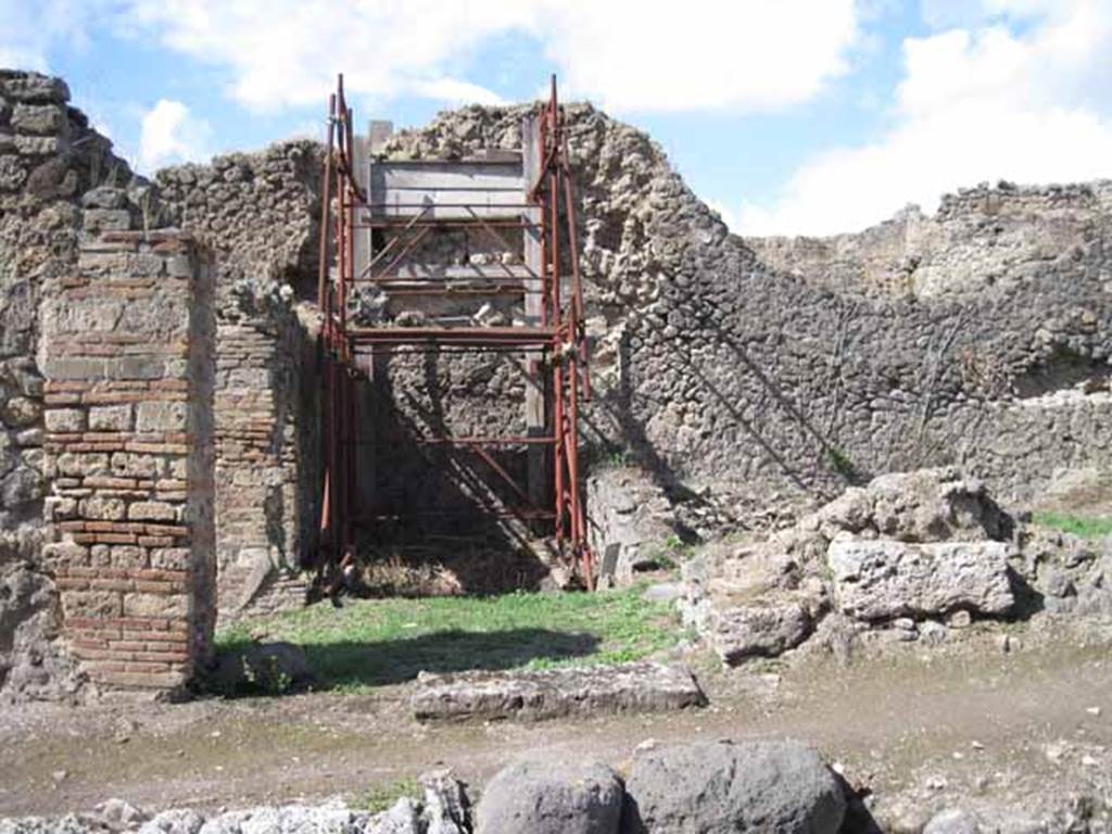 I.2.31 Pompeii. September 2010. Looking north to entrance doorway (cill or threshold still there). The green grassed area would have been one rear room of the bar at I.2.1. The other rear room would have been where the scaffolding is now. Photo courtesy of Drew Baker.