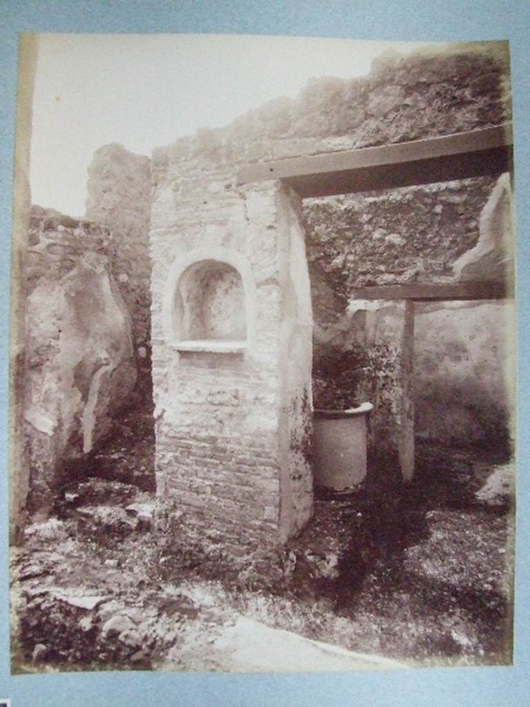 I.3.30 Lararium in peristyle at foot of straight flight of stairs. Old undated photograph courtesy of the Society of Antiquaries, Fox Collection.
According to Boyce, in the west wall of the peristyle was an arched niche. Its walls were adorned with painted flowers. On the wall on either side of it, was painted a Lar, 34cms high, holding rhyton and situla. Below it, there was a single serpent moving towards an altar.
See Boyce G. K., 1937. Corpus of the Lararia of Pompeii. Rome: MAAR 14. (p. 24)