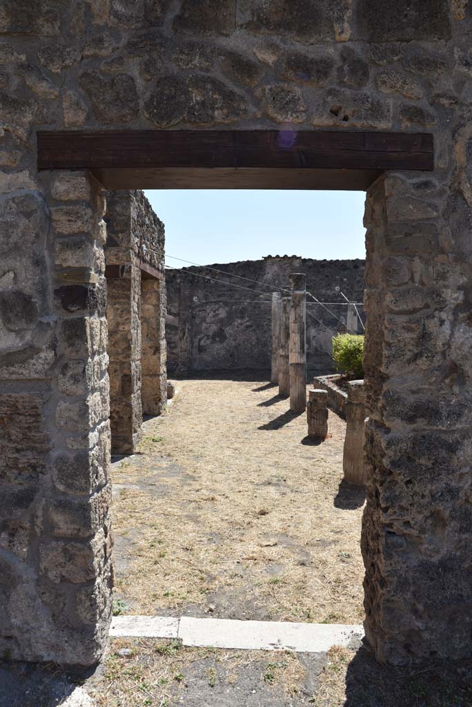 I.4.25 Pompeii. September 2020. 
Lower Peristyle 32, looking south through doorway towards east portico, from Middle Peristyle 17
Foto Tobias Busen, ERC Grant 681269 DÉCOR.
According to Jashemski –
“The long wall separating the centre (Middle) peristyle from the south (Lower) peristyle has six windows and two doors which afforded a magnificent view into the southern peristyle. The six windows each corresponded to an intercolumniation in the southern peristyle, which would indicate that in the earlier period this peristyle had been considered the more important. The twenty columns of the portico were made of brick and Sarno limestone and faced with stucco. The upper parts were fluted, the lower parts were left plain. A marble puteal stood in the portico near the north-east corner column. A gutter outlined the edges of the garden.”
See Jashemski, W. F., 1993. The Gardens of Pompeii, Volume II: Appendices. New York: Caratzas. (p.31).