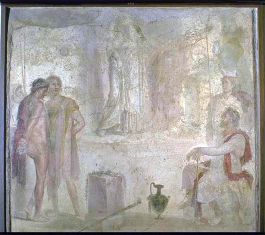 I.4.25 Pompeii. Found 1869. Room 35, east wall of exedra. Wall painting of Iphigenia in Tauris with Thoas, Orestes and Pylades.
According to Helbig, Thoas sits on the right on a stone seat covered with a leopard skin. 
Behind him, is a guard wearing a Phrygian cap and bearing a shield in his left hand.
Orestes wearing a red cloak looks melancholy.
Pylades, wearing a yellow and light purple cloak, looks livelier, a mixture of fear and defiance.
A second guard, with face covered and holding two spears, stands behind the prisoners.
At the rear is a staircase that leads to a temple platform on which Iphigenia moves slowly towards the stairs.
The top of the picture is destroyed but it is likely she is looking towards the visitors. 
She is probably carrying the Tauran Artemis idol on her left shoulder.
Now in Naples Archaeological Museum. Inventory number 9111.
See Helbig, W., 1868. Wandgemälde der vom Vesuv verschütteten Städte Campaniens. Leipzig: Breitkopf und Härtel, 1333, p. 295-6.