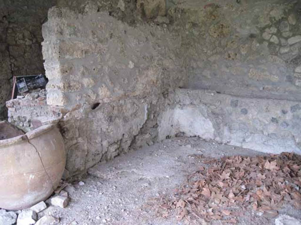 I.5.2 Pompeii. September 2010. North-east corner of fifth divided compartment, showing pipe work on east wall coming in left of image turning left through wall (north) to pot on left. Photo courtesy of Drew Baker.