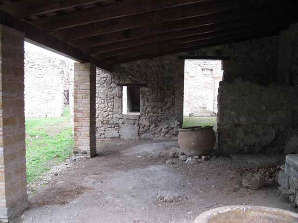 I.5.2 Pompeii. September 2010.  Looking north along east portico towards doorway to two rooms leading to industrial area. The ruined podium of the lararium can be seen on the west, left side, of the doorway. Photo courtesy of Drew Baker.