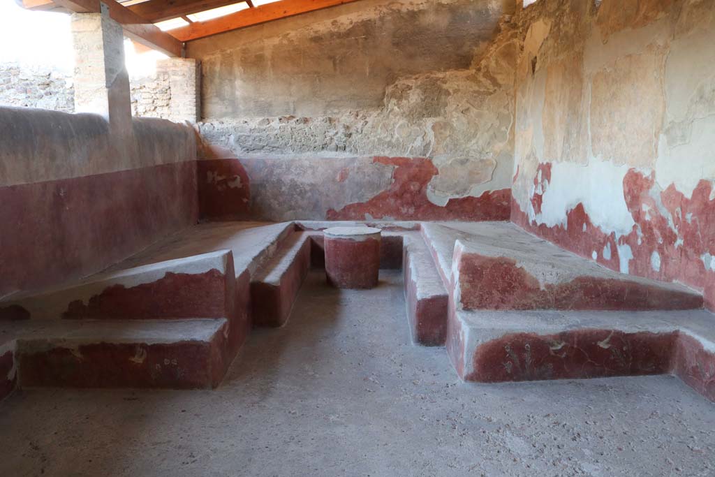 I.6.2 Pompeii. December 2018. Triclinium with table, against the west wall of the loggia.  
The circular table, the couches and the benches, were all painted with motifs of plants and birds on a red background.
Photo courtesy of Aude Durand.