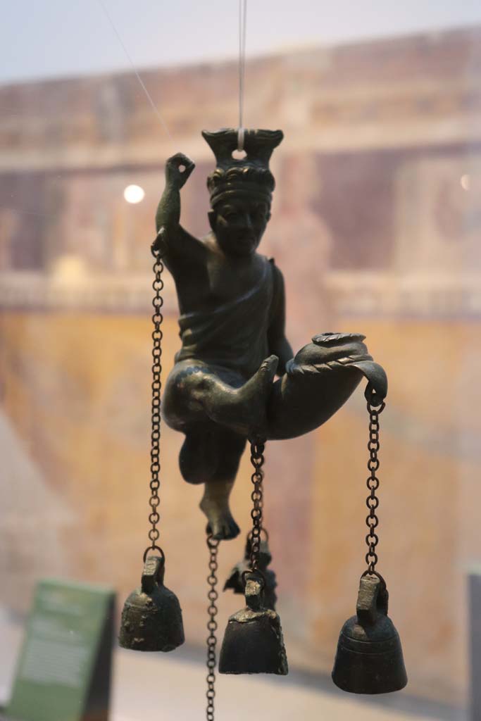 I.6.3 Pompeii. February 2021. 
Detail of bronze lamp with statuette of a satyr with a phallus from which small bells hang. 
Photo courtesy of Fabien Bièvre-Perrin (CC BY-NC-SA).