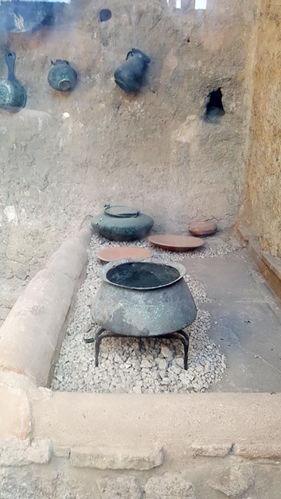 I.6.7 Pompeii. August 2023.
Looking south towards hearth at west end in kitchen with household utensils. 
Photo courtesy of Maribel Velasco.