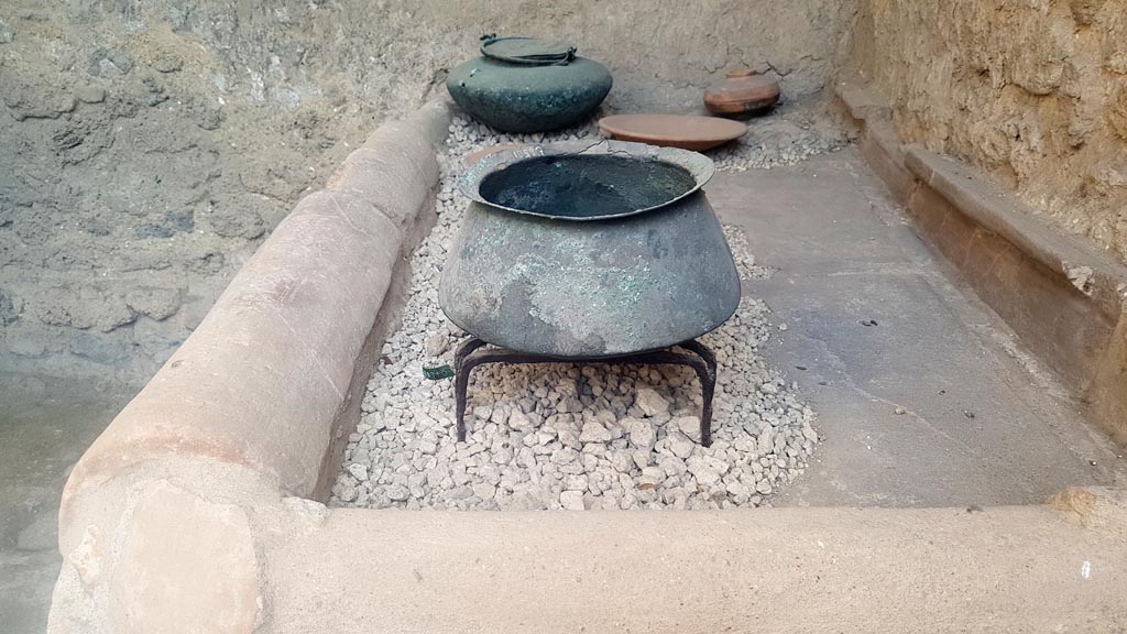 I.6.7 Pompeii. August 2023. 
Looking south towards household pots and plates displayed on top of hearth. Photo courtesy of Maribel Velasco.