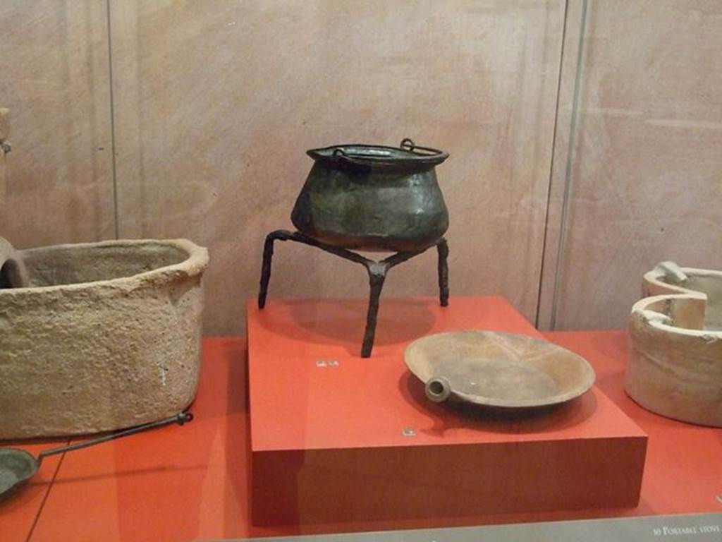 I.6.7 Pompeii. Bronze Caccabus or shallow cooking pot (at rear on tripod). SAP 4916. 
Photographed at “A Day in Pompeii” exhibition at Melbourne Museum. September 2009.