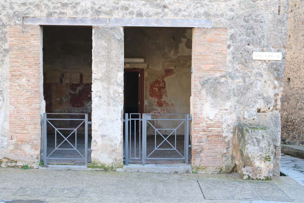 I.6.12 Pompeii. December 2018. 
One entrance, divided into two by a pillar. On the right are the remains of a street altar. Photo courtesy of Aude Durand.
According to Maiuri –
Near the corner of the shop at no.12, and therefore at the crossroads formed by the intersection of the Via dell’Abbondanza with the roadway between Insulae IV and VI of Reg. I, and Insulae I and VII of Reg. IX (so-called Vicolo di Tesmo), there is the usual masonry altar (height 1.06m) which would have been brought to light at the beginning of the new excavations on the Via dell’Abbondanza. 
Only a few insignificant traces remain of the sacred figuration painted on the plaster above the altar’s floor.
See Notizie degli Scavi, 1929, (p. 428-9).
(Ara Compitale –
Presso l’angolo della bottega n.12 ed in corrispondenza, perciò, del quadrivio formato dall’incrocio della Via dell’Abbondanza con il vicolo fra le insulae IV e VI della Reg. I e le insulae I e VII della Reg. XI (cd. Vicolo di Tesmo) non manca la consueta ara compitale in muratura (alt. m. 1.06) che dove essere messa in luce fin dall’inizio dei nuovi scavi sulla Via dell’Abbondanza. Non restano che poche ed insignificanti tracce della figurazione sacra dipinta sull’intonaco al disopra per piano dell’ara.)