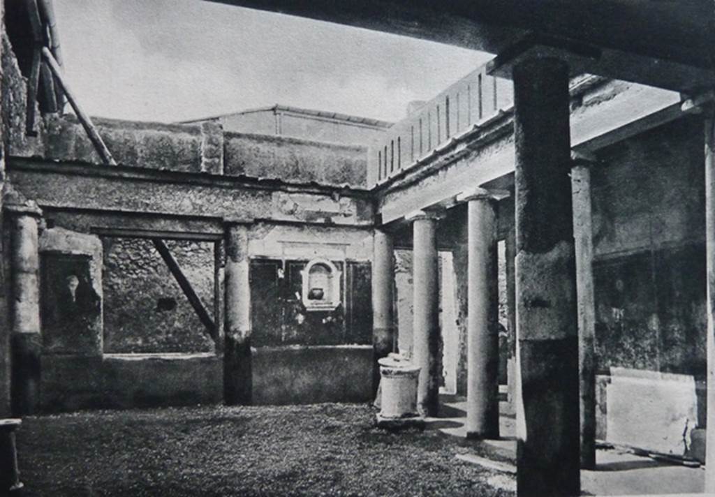 I.7.7 Pompeii. Old undated photograph. Pseudoperistyle, with lararium niche seen in west wall. According to Boyce, the arched niche was adorned with a stucco aedicula façade and a cornice running around the inside walls. The area of the wall immediately around the niche was painted as part of the decoration, into which the niche was set in a panel. There was no lararium painting and no other indication of religious use. It is called an edicoletta larare in the report and probably was a shrine, as there is none elsewhere in the house. Not. Scavi, 1927, 27.
See Boyce G. K., 1937. Corpus of the Lararia of Pompeii. Rome: MAAR 14. (p.25, no.39)