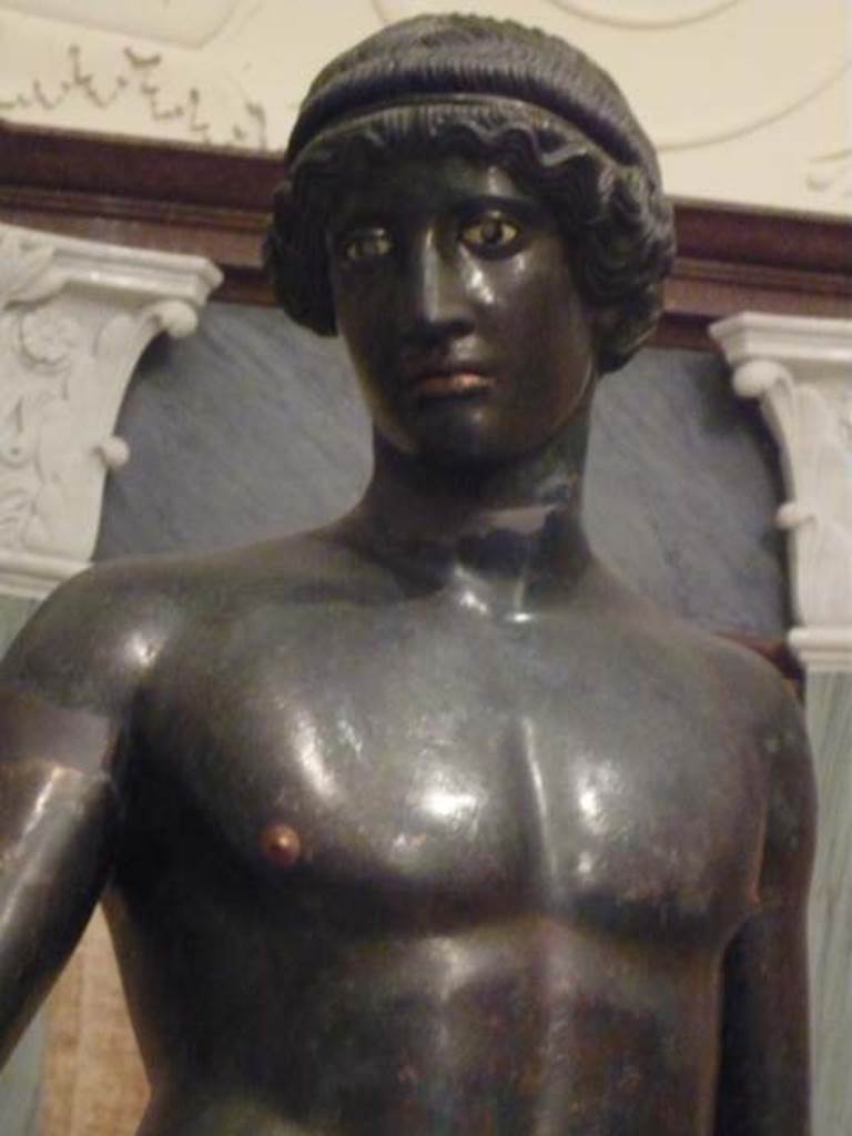 I.7.11 Pompeii. 2010. Front view of bronze statue of the ephebo from south side of atrium near tablinum. 
The lifelike eyes were inlaid with corneas of white glass paste, cut to receive irises of a different colour now lost.
Photo courtesy of Buzz Ferebee.