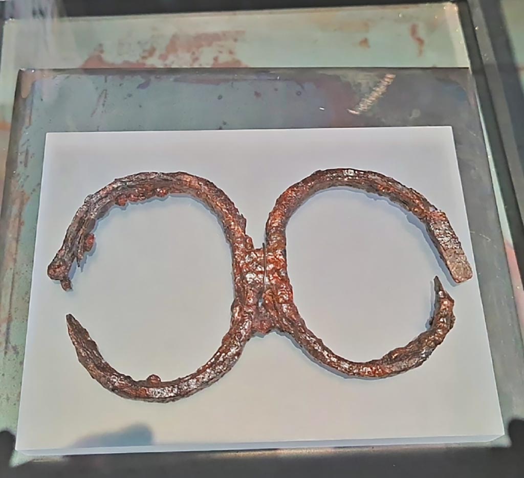 I.7.11 Pompeii. March 2024. Photo courtesy of Giuseppe Ciaramella.
Iron slave shackle with double ring. Ist century AD. (Ceppo per schiavi a doppio anello, Ferro, I sec. d.C.)
On display in exhibition entitled – “L’altra Pompei, vite comuni all’ombra del Vesuvio”.