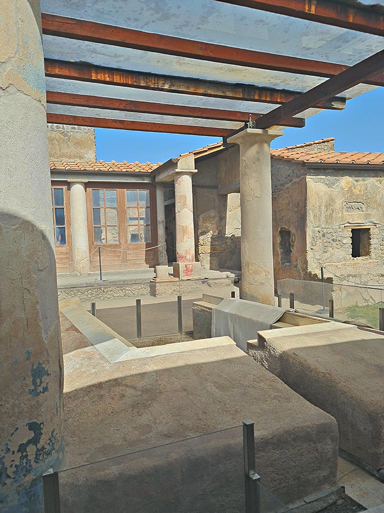 I.7.12 Pompeii. September 2024. 
Looking north-east across triclinium in garden towards north portico and windows from cubiculum, on right.
Photo courtesy of Giuseppe Ciaramella.