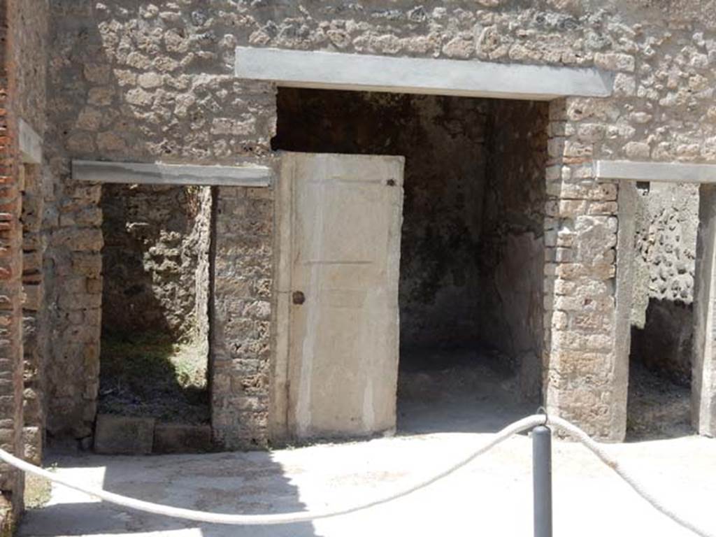 I.7.19 Pompeii. May 2017. Doorways to rooms in north-west corner of atrium. Photo courtesy of Buzz Ferebee.
According to NdS –
“Cubiculum which, due to its unusual shape, seems to have been adapted in the more recent times into an exedra, (measuring 2.40 x 1.80m), originally open onto the atrium. It was possible to draw the complete imprint of the door that with a single leaf served to close the cubiculum, and inside the wooden framework of the bed that occupied almost the entire width of the small room. At the ends of the bed and especially at the lower headboard, the pieces of bone that inlaid the wooden panels with geometric design remained in the compactness of the ash layer. The ceiling was flat, and above it there were traces of the upper room.  
Near the entrance of this cubiculum, it was possible to make the plaster of the body of an 8 to 10 year old boy who, from his special position (the head sunk into the lapilli and the lower half of the body into the ashes), was thought to have fallen headlong from the upper floor of the house, with a wicker basket that he carried tightly with one of his arms and which was found next to him (fig.2, p. 360).
The unfortunate boy fell, with one of his hands brought variously to his mouth to protect himself from the asphyxiating fumes, and with the other hand raised aloft as if to try to save the basket in the fall, with which, he had deluded himself into thinking he was carrying a few provisions for his desperate escape.”
(Cubicolo che per la sua forma inusitata sembra essere stato adattato negli ultimi tempi nel vano di un exedra originariamente aperta sull’atrio (m. 2.40 x 1.80). si pote trarre l’impronta completa della porta che con un sol battente serviva a chiudere il cubicolo, e all’interno l’impronta della impalcatura in legno del letto che occupava quasi tutta l’ampiezza del piccolo ambiente. Alle due testate del letto e soprattutto alla testata inferiore sono rimaste nella compattezza dello strato di cenere le filettature in osso che intarsiavano di disegno geometrico i pannelli in legno. Il soffitto e piano e al disopra di esso restano le tracce dell’ambiente superiore.
Presso l’ingresso di questo cubicolo si pote eseguire la forma in gesso del corpo di un fanciulletto di otto o dieci anni che dalla sua speciale positura (il capo affondato nel lapillo e la meta inferiore del corpo nella cenere) si dove pensare fosse precipitato a capo fitto dal piano superiore della casa con un cestella di vimini che recava stretto con l’uno dei bracci e che gli fu trovato accanto (fig.2, p. 360).
Precipito il disgraziato fanciullo con l’una delle mani portata variamente alla bocca per ripararsi dalle esallanoni asfissianti e con l’altra mano sollevata in alto come per tentar di salvare nella caduta il cestello con cui si era illuso di portar con se poche cibarie per la disperata sua fuga.)
See Notizie degli Scavi, 1929, (p.359-60).