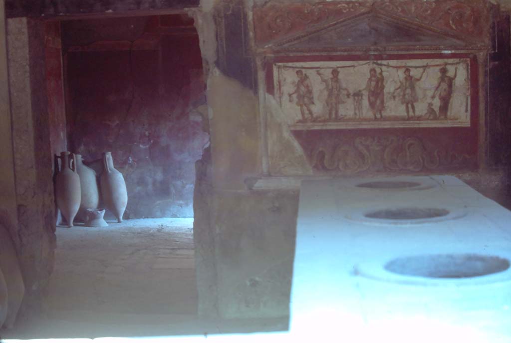 I.8.8 Pompeii. August 1976. Looking south across top of counter towards lararium, on right.
Doorway to rear room, on left. Photo courtesy of Rick Bauer, from Dr George Fay’s slides collection.
