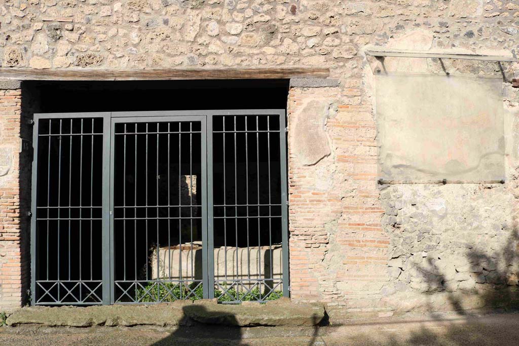 I.8.15 Pompeii. December 2018. Looking north to entrance doorway on Via di Castricio. Photo courtesy of Aude Durand.
According to PPM, 
“All of the south-west area of the insula 8 was reserved for commercial activity and sales, since part of this property was used as a caupona with its characteristic sales podium in the entrance room, and with the rooms for the customers (at the rear on the left).
The eastern part, with the neighbouring dwelling at I.8.14, was used as a “colouring” plant. No colours had been found here because the site was not functioning in 79AD, but the oven of small dimensions with its slow drying plate, three manual reels/mules and nine mortars with pestles left in the room, leave no doubt about its use.  
This workshop probably had the same proprietor as the caupona, in that the entrance doorway opening into it, opened from the caupona.”
See Carratelli, G. P., 1990-2003. Pompei: Pitture e Mosaici: Vol. I. Roma: Istituto della enciclopedia italiana, p. 844.