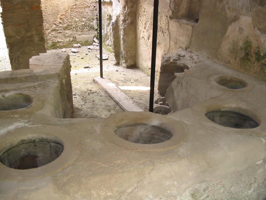 I.8.15 Pompeii. May 2003. 
Looking north across counter with five remaining embedded dolia, and a broken one, centre right. Photo courtesy of Nicolas Monteix.