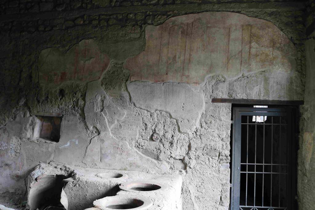 I.8.15 Pompeii. December 2018. 
South end of east wall with painted decoration above doorway, leading to kiln and plant for production of pigments. Photo courtesy of Aude Durand.