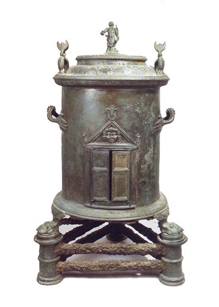 I.8.17 Pompeii. Bronze cylindrical food warmer found in a made to measure niche under the stairs in the servants’ quarters. 
It has a lid with three handles, one in the form of a statuette of Triton in the centre and two dolphins at the edges.
On the body are two handles in the form of hands, double doors at the front are surmounted by a pediment with palm leaves and a Medusa's head.
At the base, lion’s paw feet rest on three pillars connected by a double iron bar.
Now in Naples Archaeological Museum. Inventory number 6798.
See Conticello, B., Ed, 1990. Rediscovering Pompeii. Rome: L’Erma di Bretschneider, p. 173, no. 59.