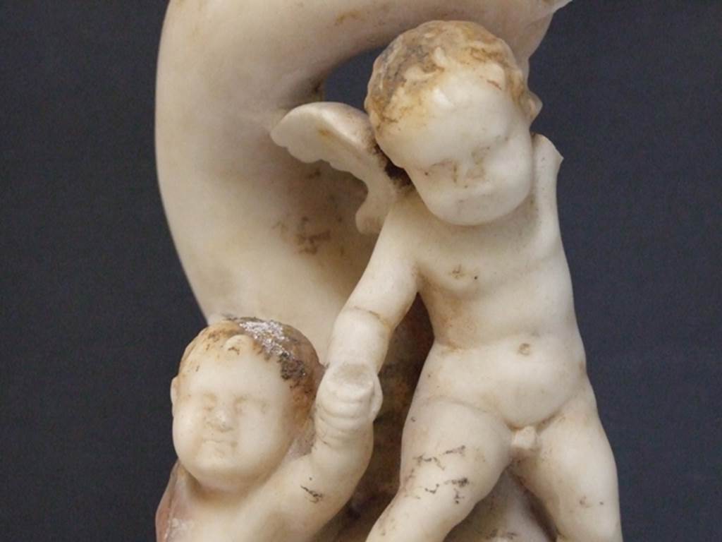 I.9.14 Pompeii. 2009. Marble fountain statuette. Two Amorini riding on dolphin.  
Detail of a cupid.  SAP inventory number 8128.  Found in 1951.
