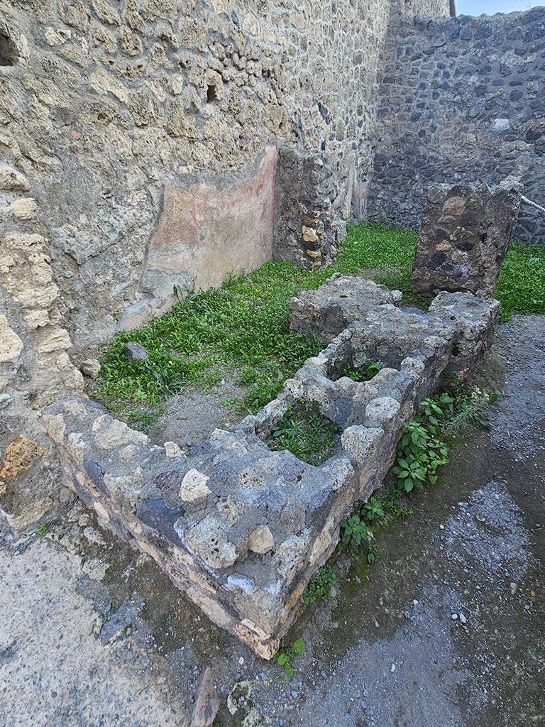 I.10.2, Pompeii. November 2024.
Remains of podium/counter, originally with two dolia and a hearth. Photo courtesy of Annette Haug.