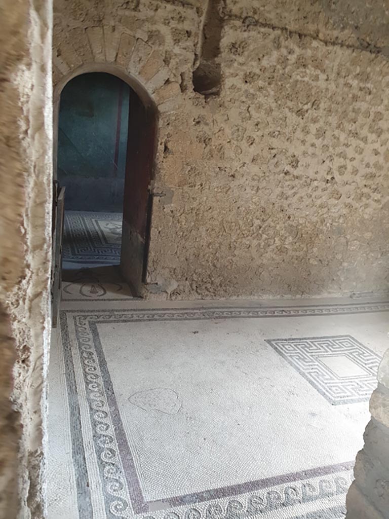 I.10.4 Pompeii. August 2023. 
Room 47, looking south through doorway across flooring towards arched doorway into caldarium. 
Photo courtesy of Maribel Velasco.