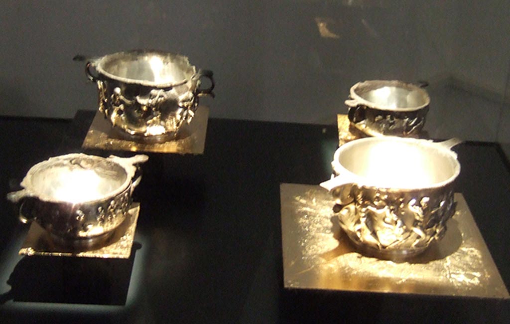 I.10.4 Pompeii. Four silver scyphi. The two taller and wider ones are decorated with the adventures of Hercules.
The two smaller ones with the worship of Dionysus. 
Part of the 115 pieces of Silver found in a chest in the underground storerooms. 
Now in Naples Archaeological Museum. Inventory numbers 145506 and 145507 (Hercules, front right and rear left respectively).
Inventory numbers 145508 and 145509 (Dionysus, rear right and front left respectively).
See Guzzo, P. (A cura di), 2006. Argenti a Pompei. Milano, Electa. p.198-201.