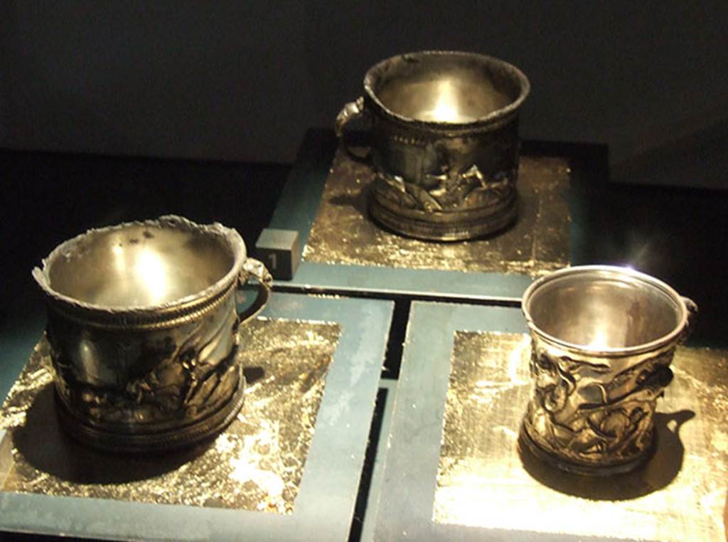 I.10.4 Pompeii. Silver modioli. The left two are decorated with games and the one on right with animals. 
Part of the 115 pieces of Silver found in a chest in the underground storerooms. 
Now in Naples Archaeological Museum. Inventory numbers 145510 (centre) 145511 (left) and 145512 (right).
See Guzzo, P. (A cura di), 2006. Argenti a Pompei. Milano, Electa. p.202-3.