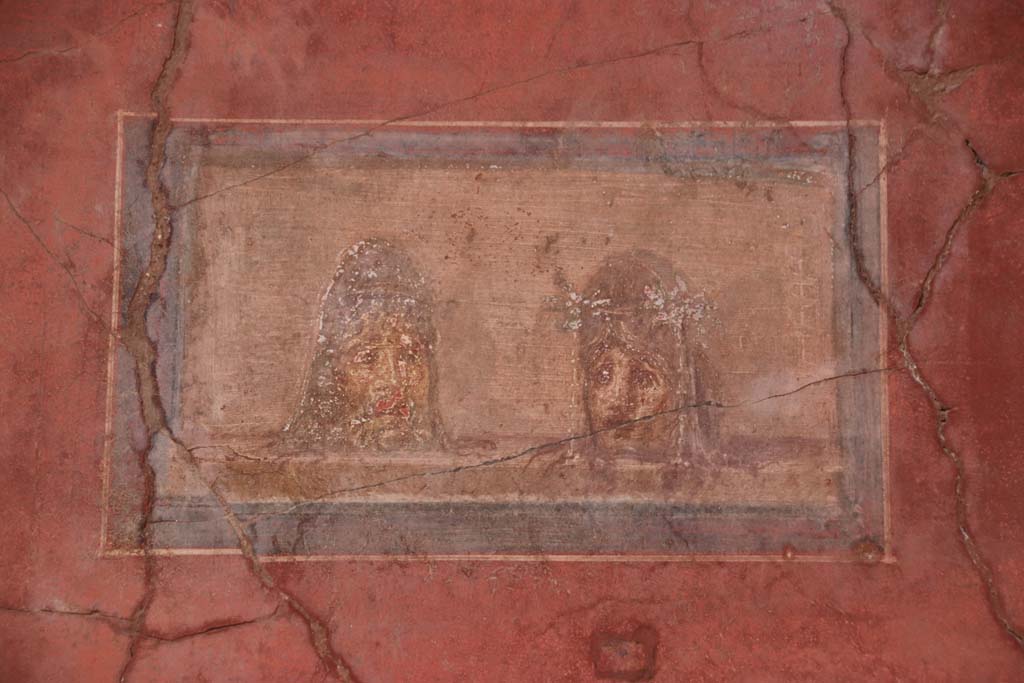 I.10.4 Pompeii. September 2021. 
North wall in north-east corner of atrium, detail of painted panel with theatrical masks. Photo courtesy of Klaus Heese.