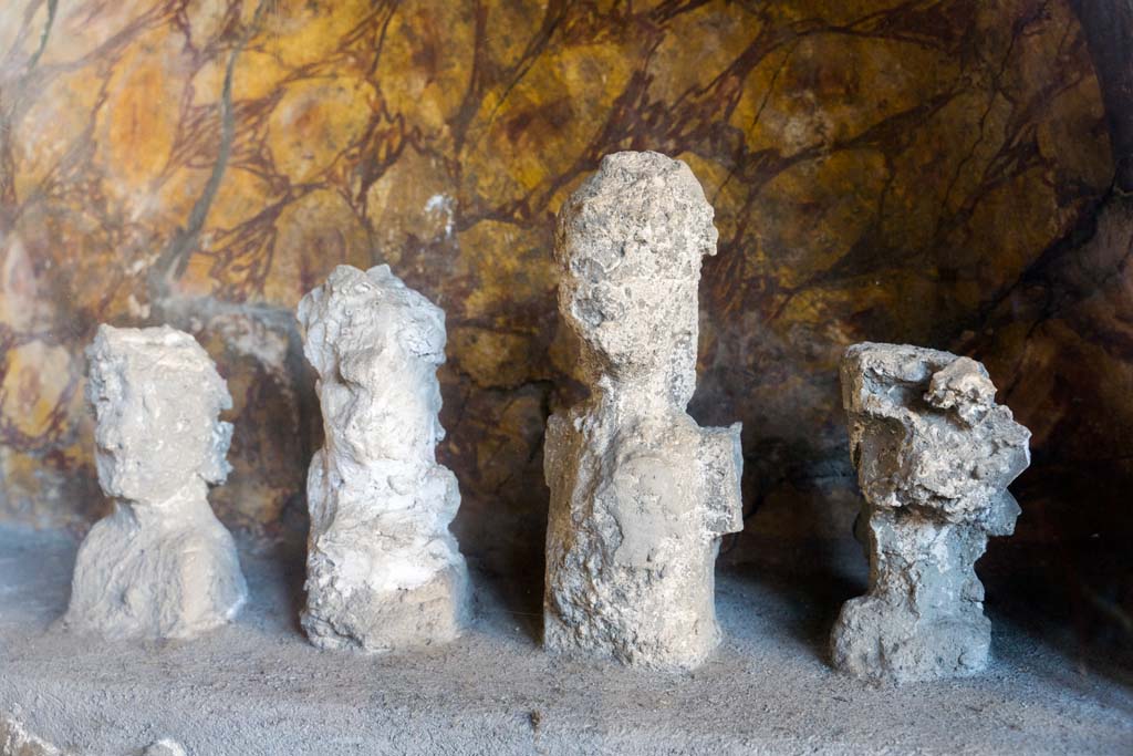 I.10.4 Pompeii. April 2022. 
Alcove 25, lararium or domestic shrine, plaster casts of the original wooden ancestor images. Photo courtesy of Johannes Eber.
According to Cicirelli, these are imagines maiorum, ancestor images, and were accompanied a statuette of a sitting youth, identified as a lar.
See Stefani, G. (Ed), 2003. Menander: La casa del Menandro di Pompei. Milano: Mondadori Electa. (p. 187).