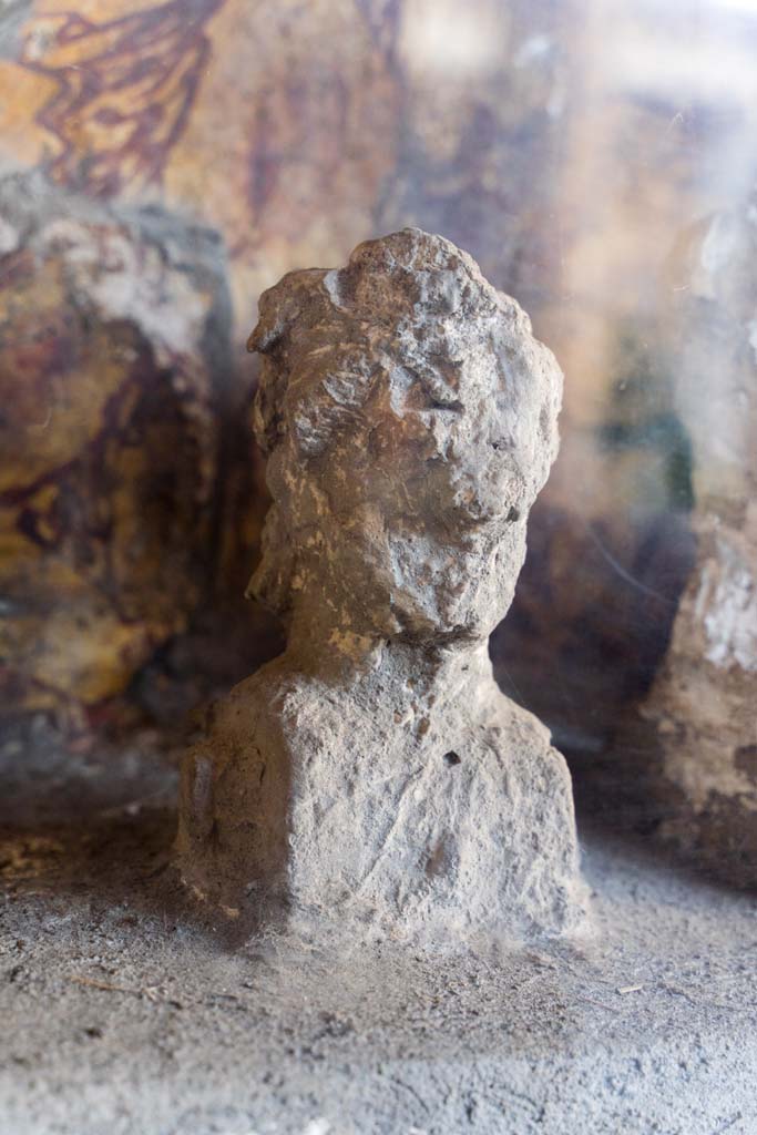 I.10.4 Pompeii. April 2022. 
Alcove 25, detail of plaster cast, on the left, on the lararium or domestic shrine. (Image 1). 
Photo courtesy of Johannes Eber.