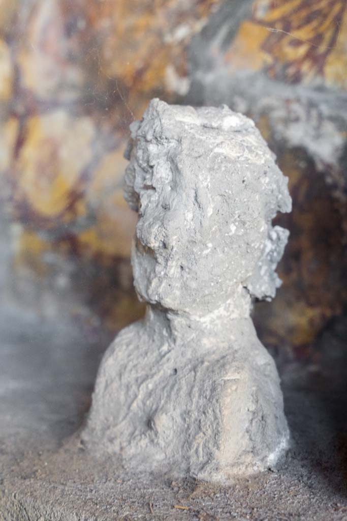 I.10.4 Pompeii. April 2022. 
Alcove 25, detail of plaster cast, on the left, on the lararium or domestic shrine. (Image 2). 
Photo courtesy of Johannes Eber.